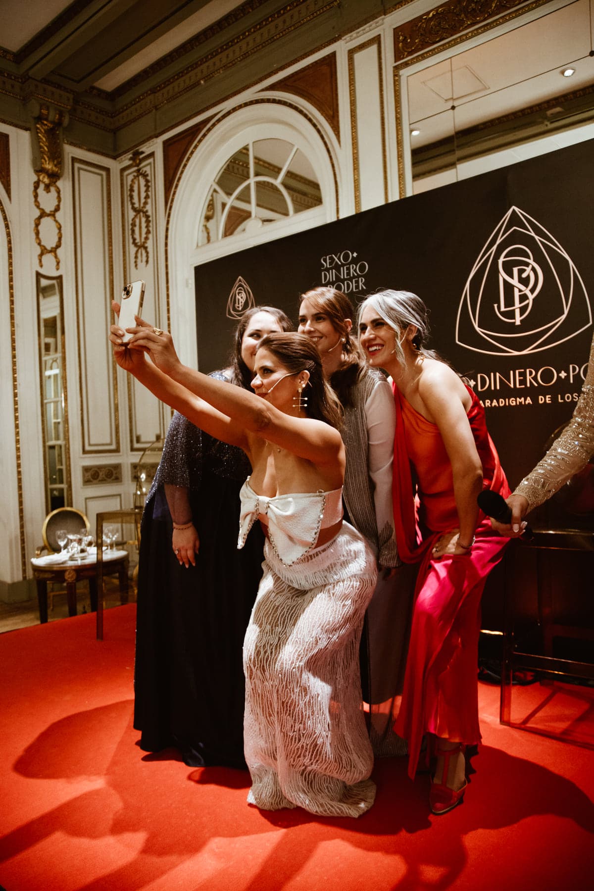 Cuatro mujeres de pie, juntas, en el salón del evento.