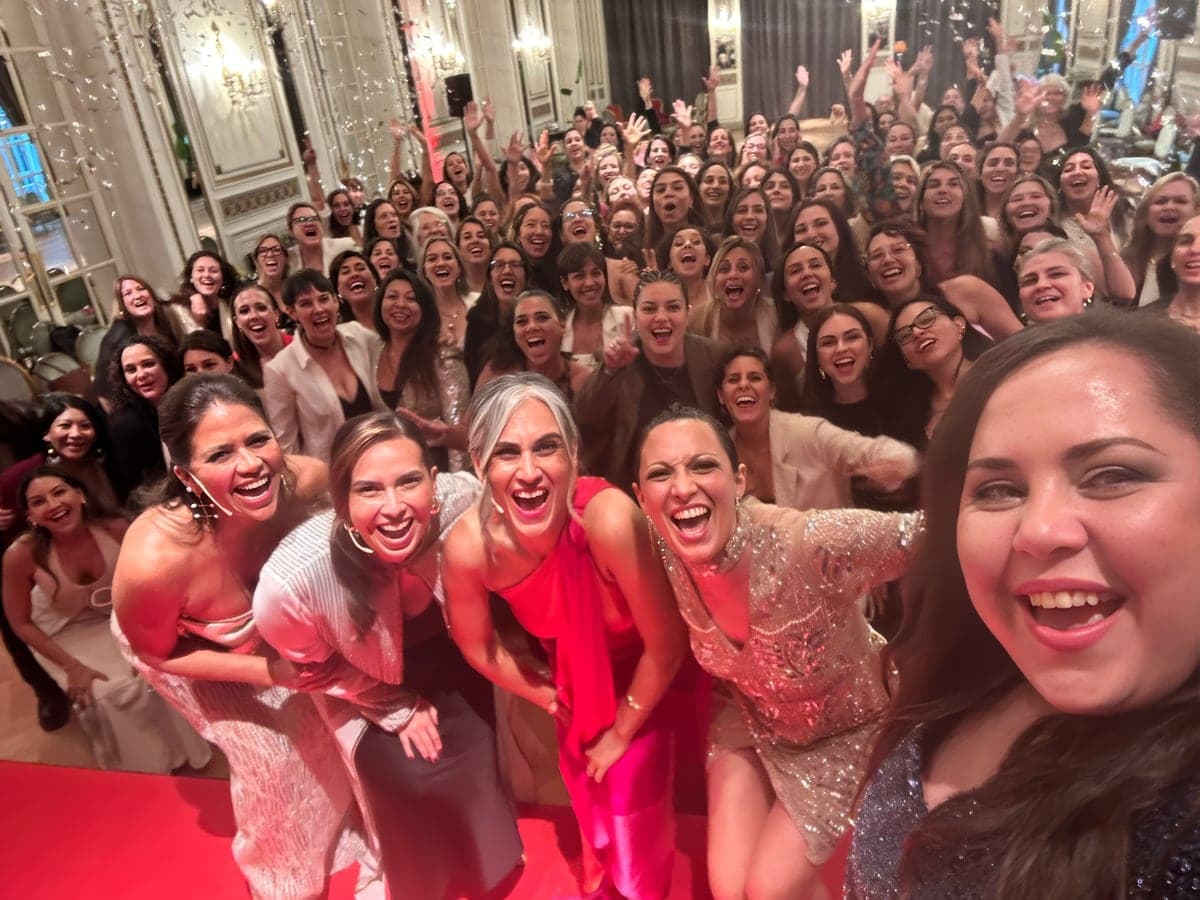 Decenas de mujeres apretadas para una foto de grupo, riendo, en el salón del evento.